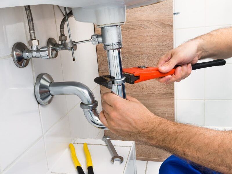 Plumber fixing tap in bathroom John G. Plumbing Drain and Sewer Cleaning