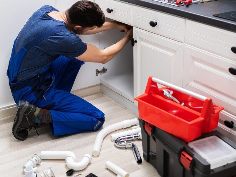 Plumber fixing pipe under sink John G. Plumbing Coombs