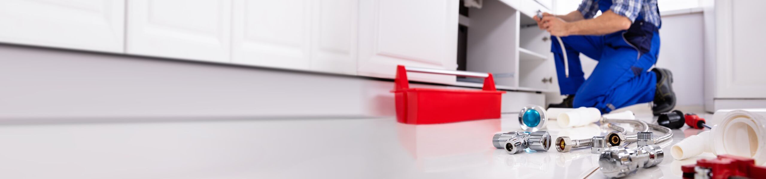 Plumber fixing pipe under sink John G. Plumbing Coombs