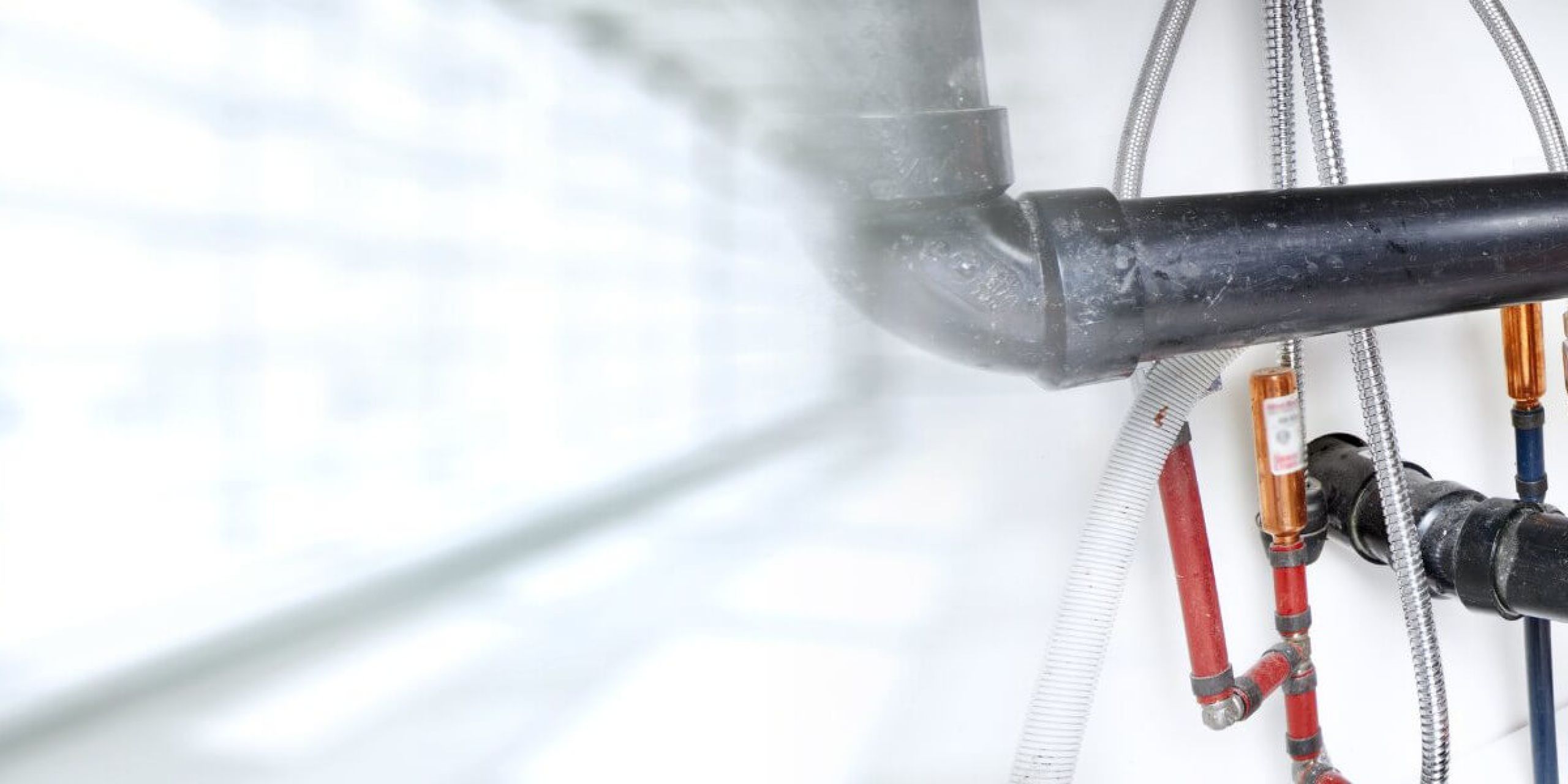 A man holding a wrench and is fixing a water pipe.