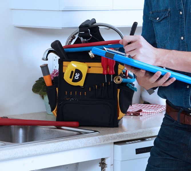 John G. Plumbing plumber with tools at house writing on clipboard