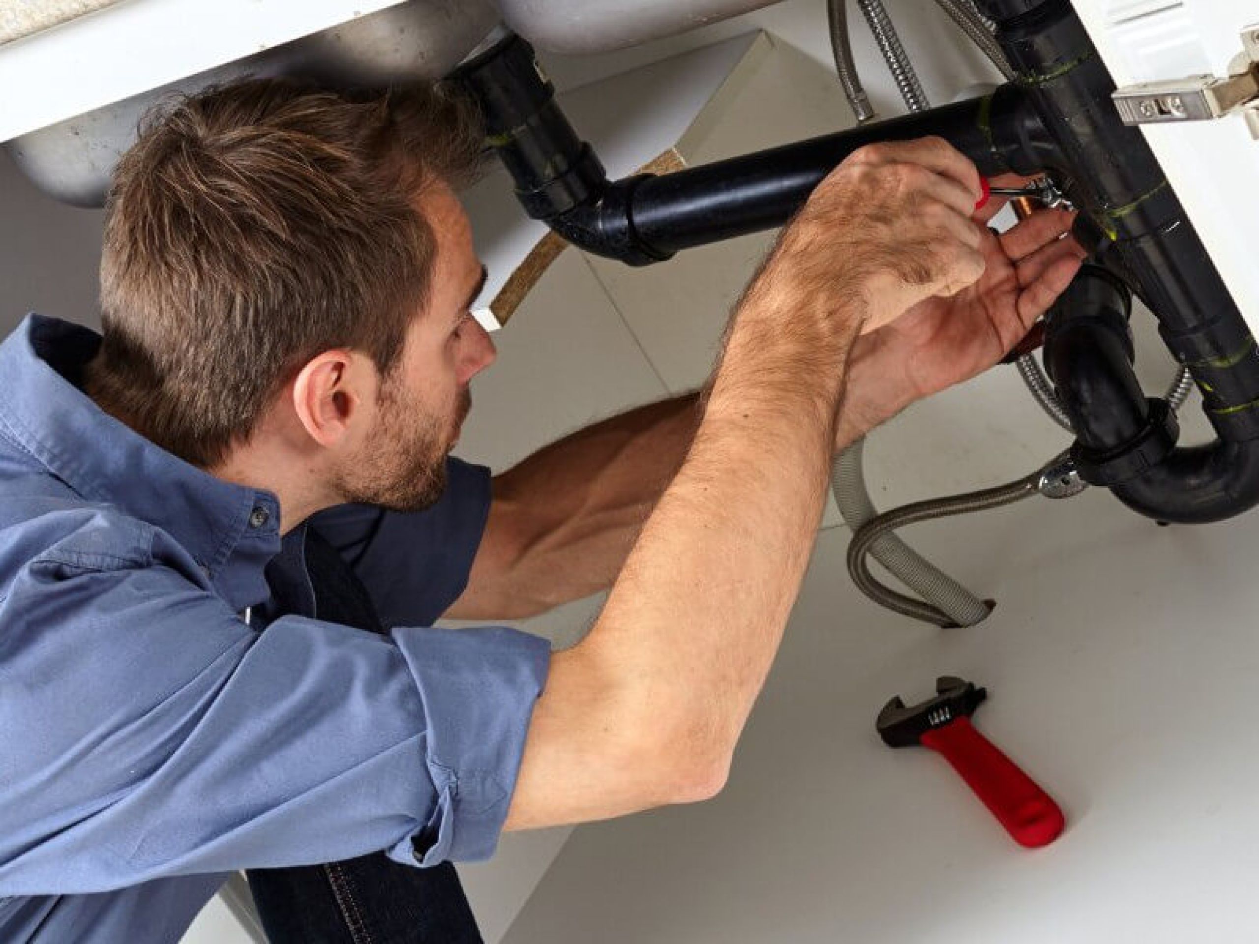 A plumber fixing a bathroom pipe.