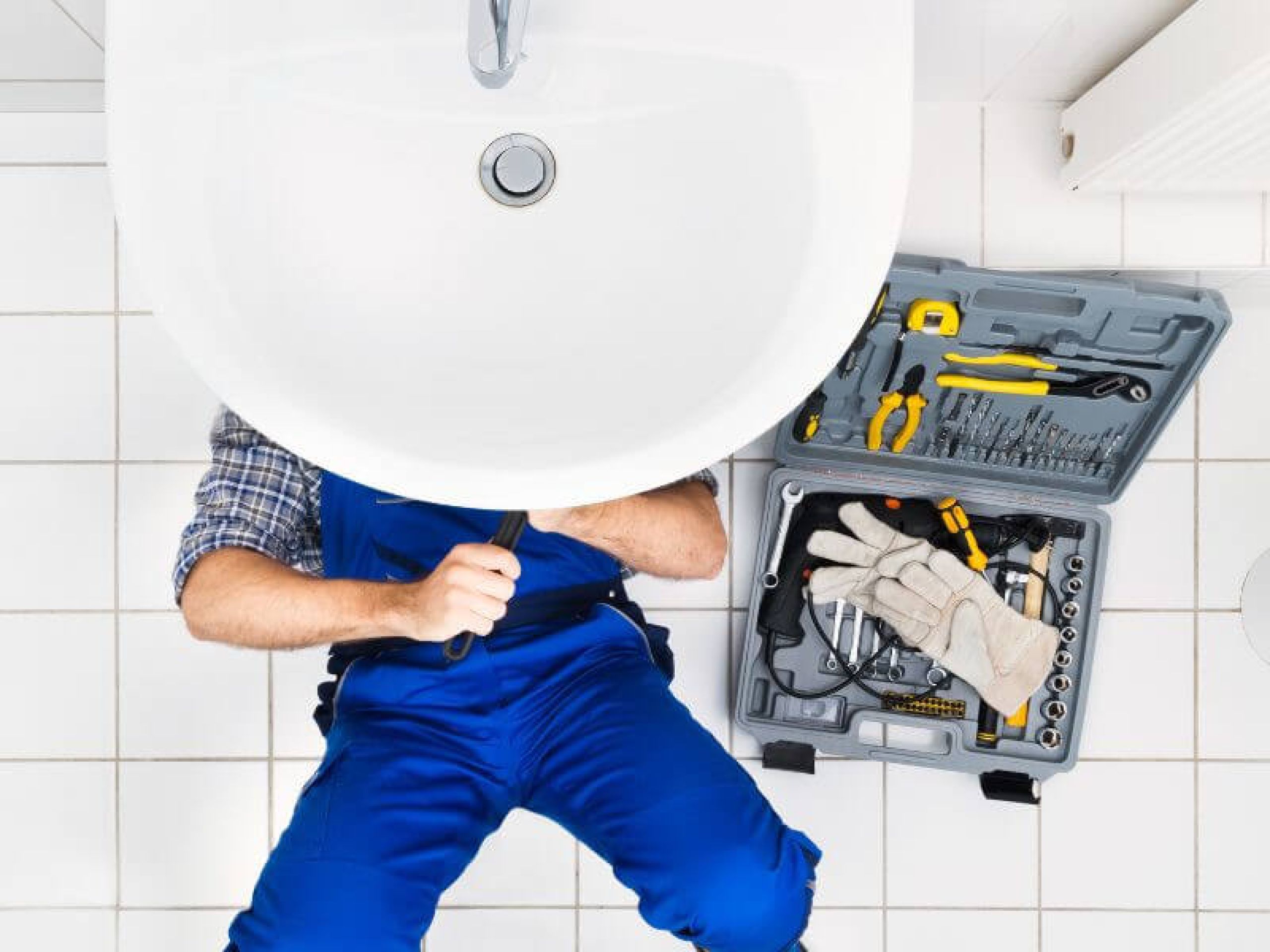 A man lying and is fixing the pipes underneath the lavatory.