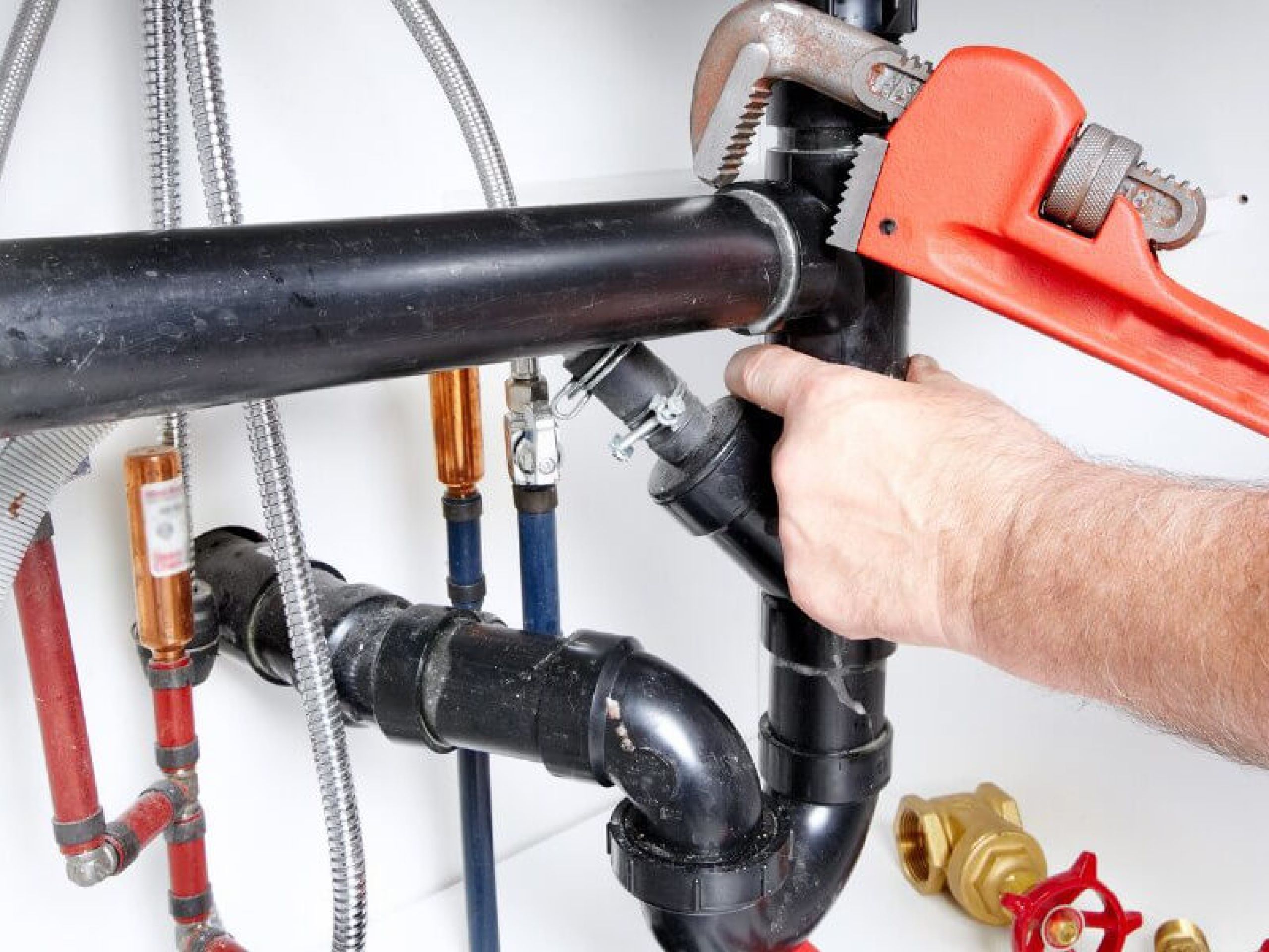 A man holding a wrench and is fixing a water pipe.