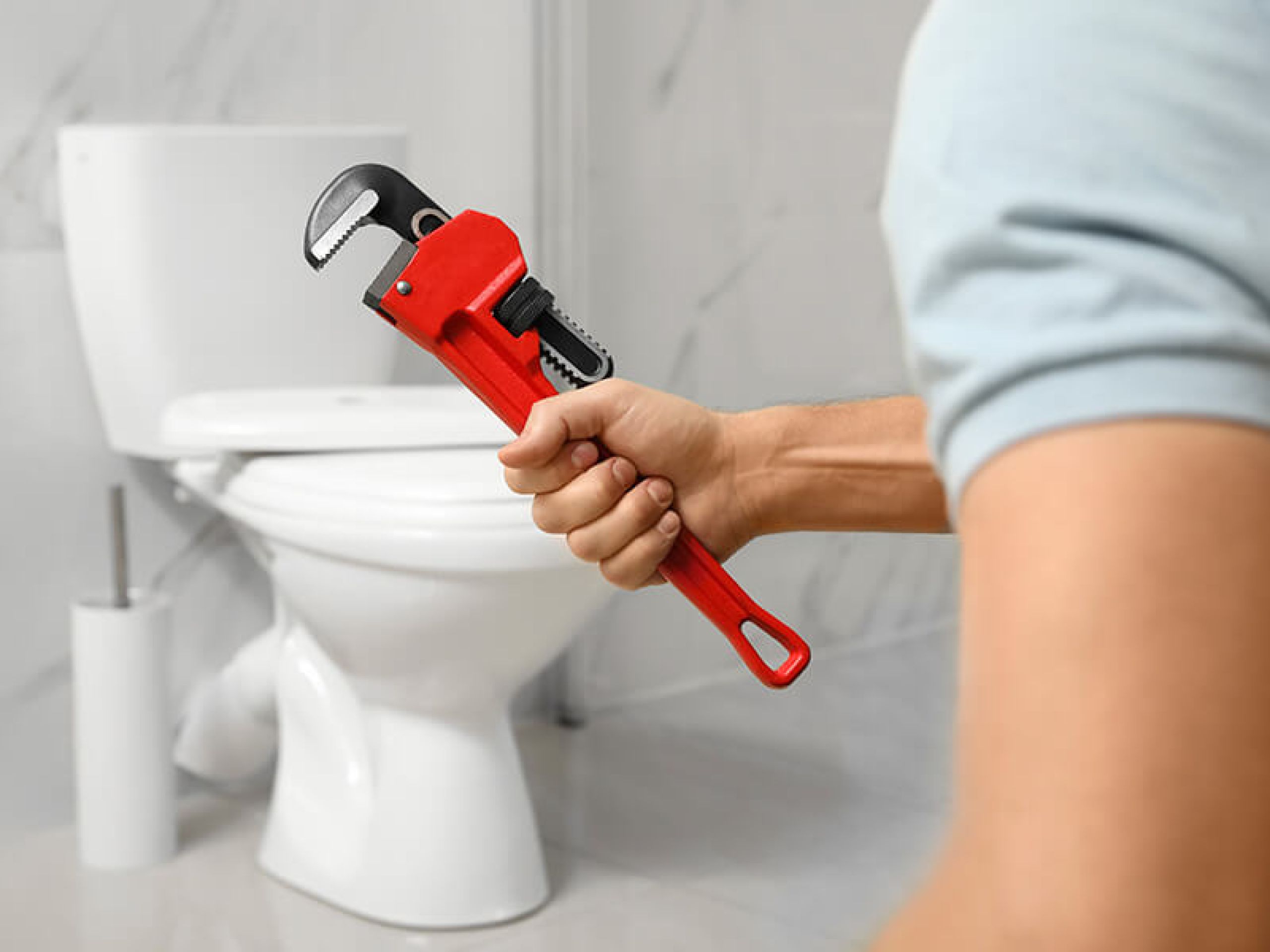 Image of red wrench in front of toilet to be replaced