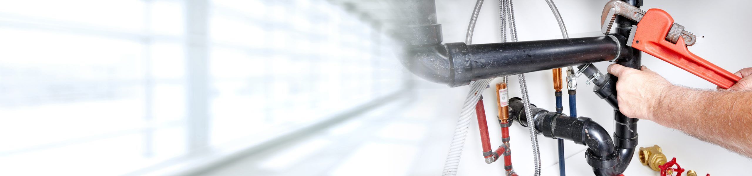 A man holding a wrench and is fixing a water pipe.