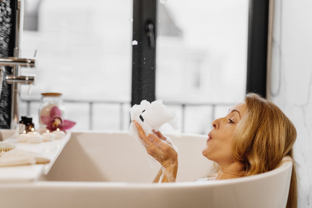 a woman blowing bubbles in the tub