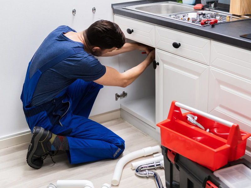 Plumber fixing pipe under sink John G. Plumbing Coombs
