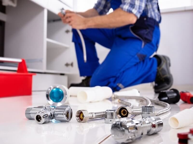 Plumber fixing pipe under sink John G. Plumbing Coombs