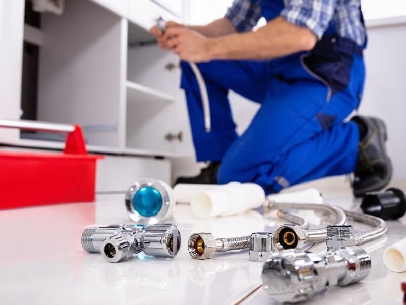 Plumber fixing tap in bathroom John G. Plumbing Drain and Sewer Cleaning