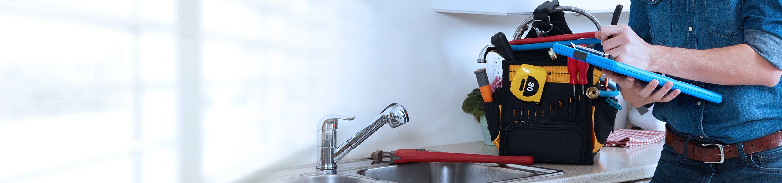 Plumber fixing pipe under sink John G. Plumbing Coombs