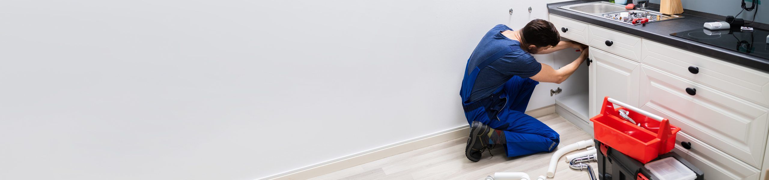 Plumber fixing pipe under sink John G. Plumbing Coombs