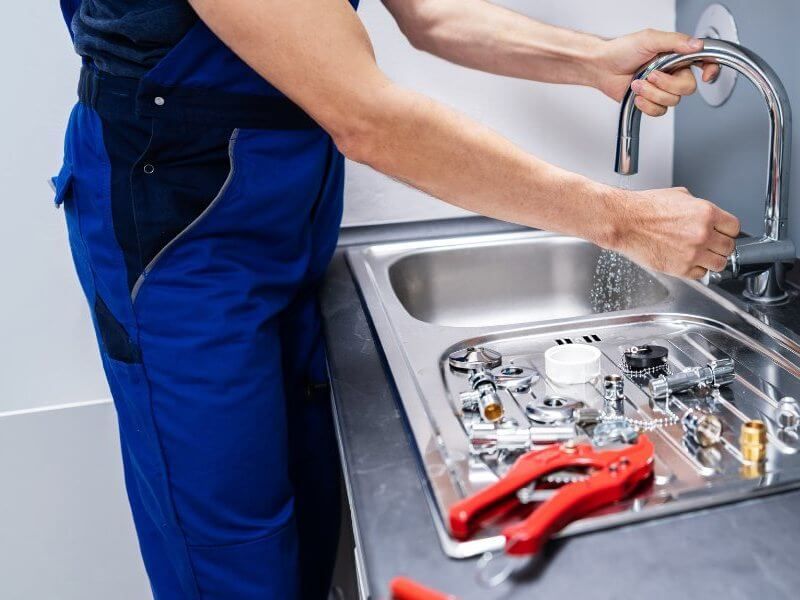 Plumber fixing tap in bathroom John G. Plumbing Drain and Sewer Cleaning