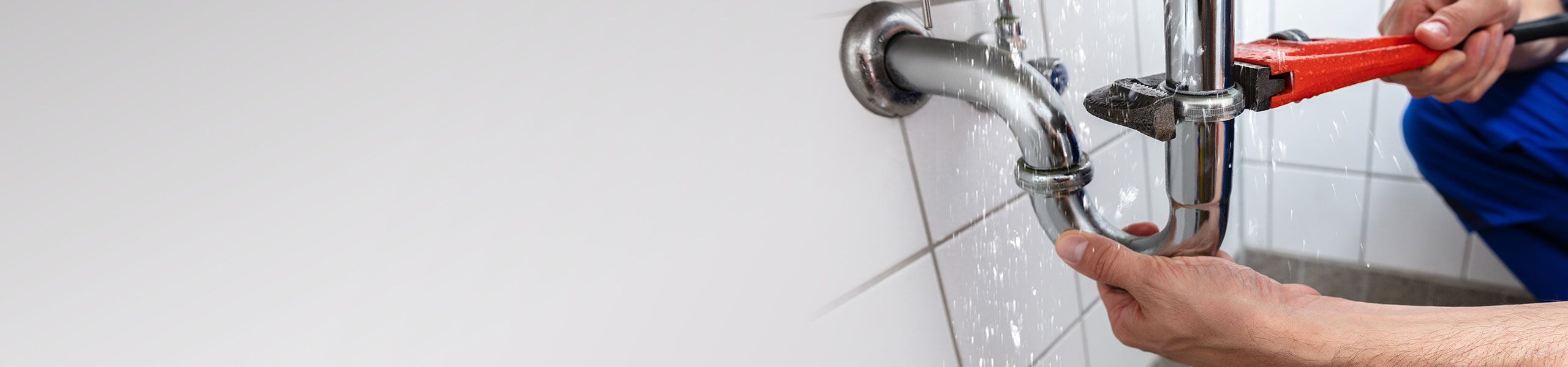 a hand holding a wrench fixing a burst pipe