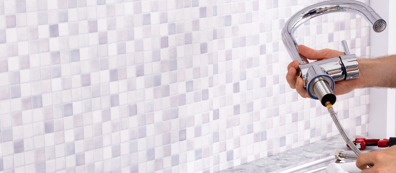 Plumber fixing tap in bathroom John G. Plumbing Drain and Sewer Cleaning