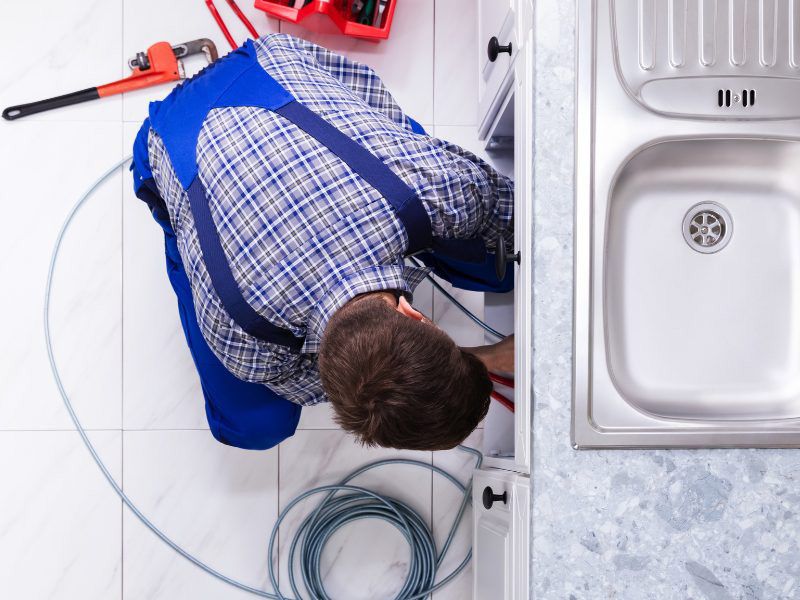 Plumber fixing kitchen tap about John G. Plumbing