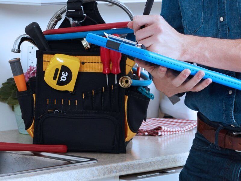 Plumber fixing pipe under sink John G. Plumbing Coombs