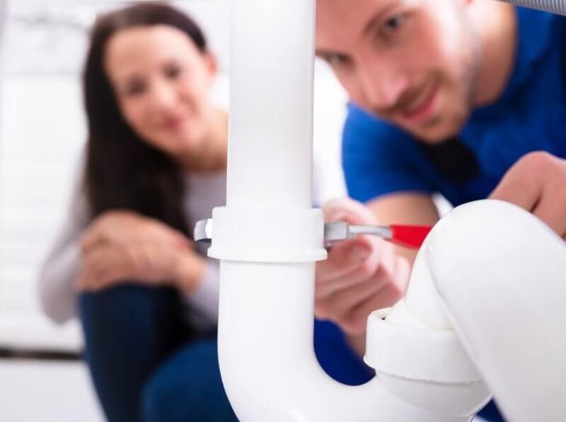 Man holding a wrench and is fixing a pipe.