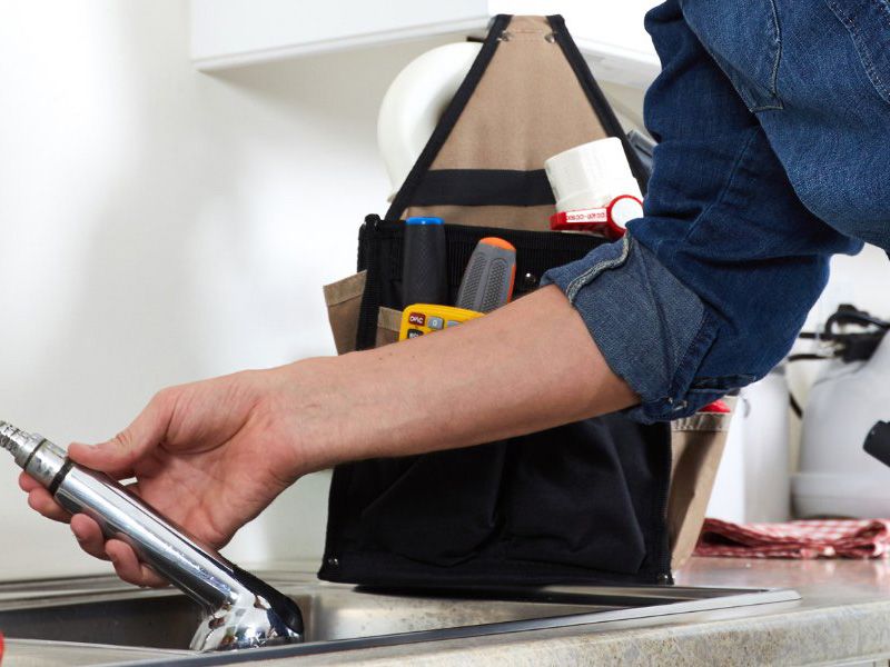 Plumber fixing tap in kitchen John G. Plumbing Gas and Plumbing Tips and News