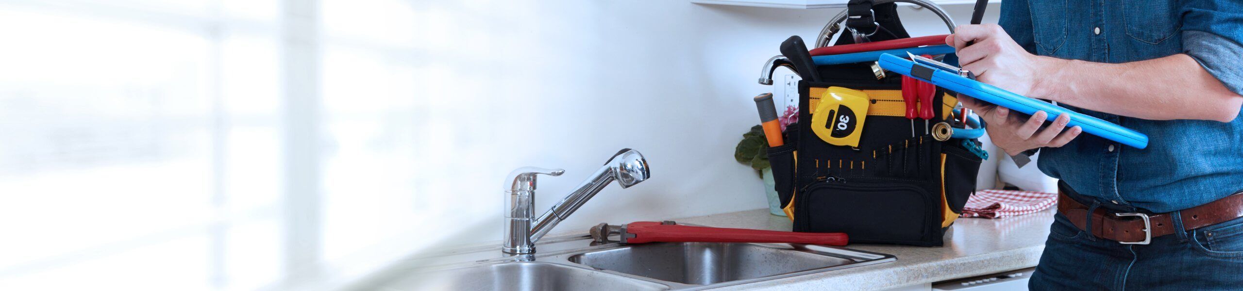 Plumber fixing pipe under sink John G. Plumbing Coombs