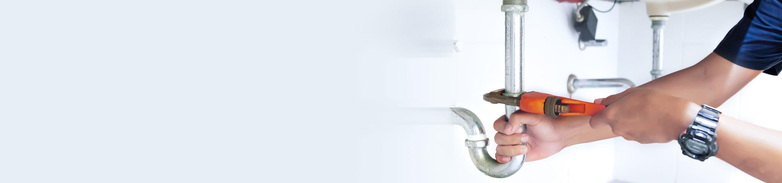 A person holding a wrench and is fixing a pipe.