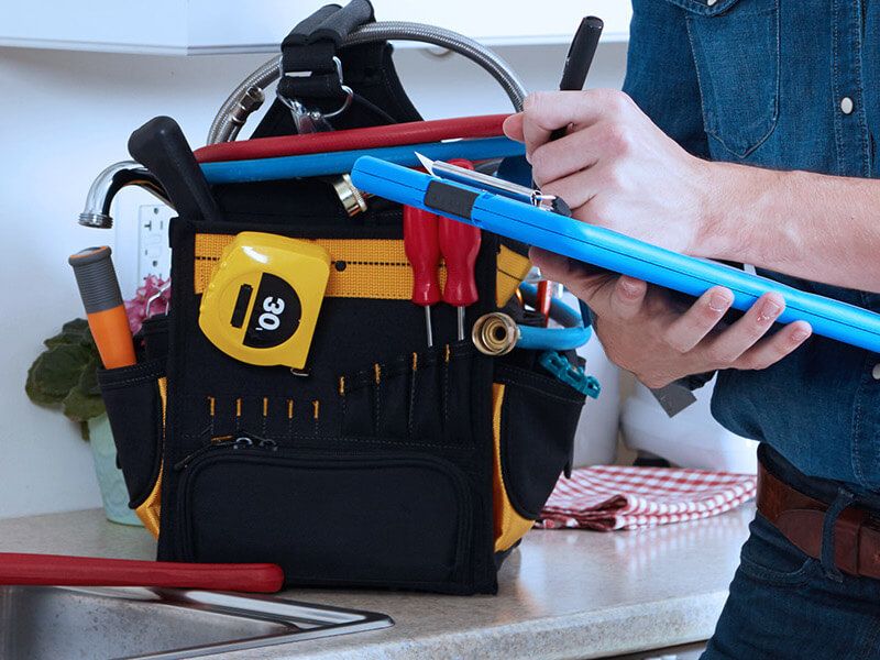 Plumber fixing pipe under sink John G. Plumbing Coombs